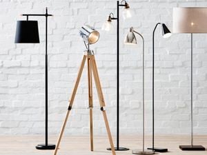 A selection of free standing modern lights with sleek stands against a white wall.