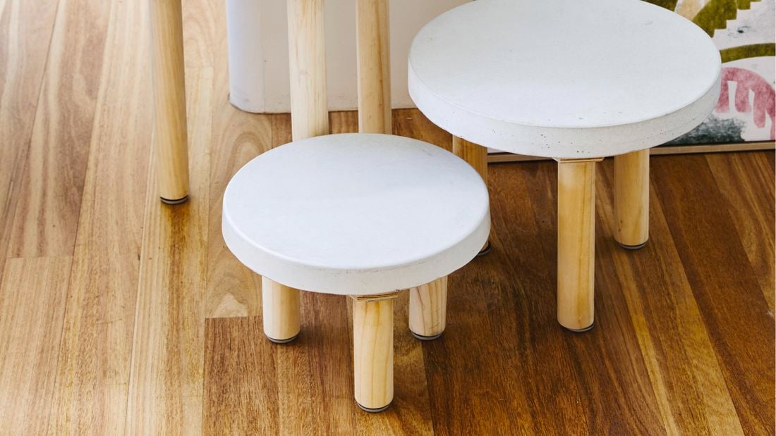 A set of two concrete paver side tables, sitting on a wooden floor