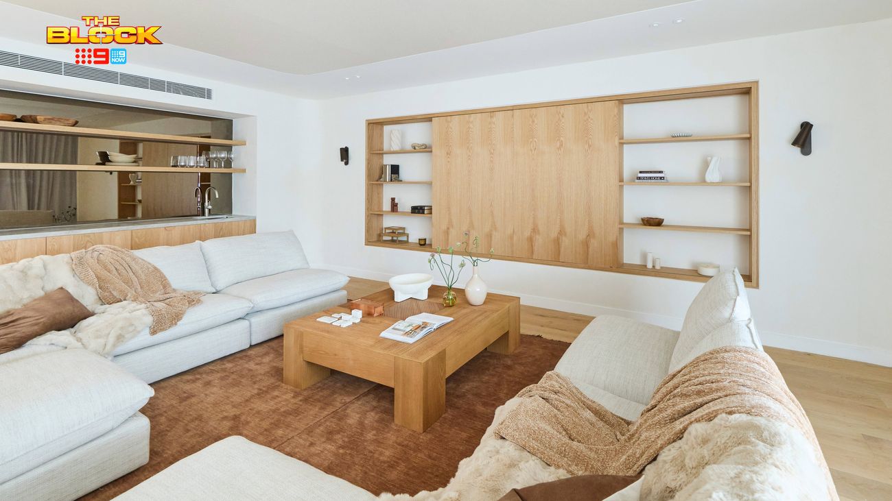 Contemporary living room featuring large neutral sofas, a timber coffee table and built-in timber shelving with concealed storage.