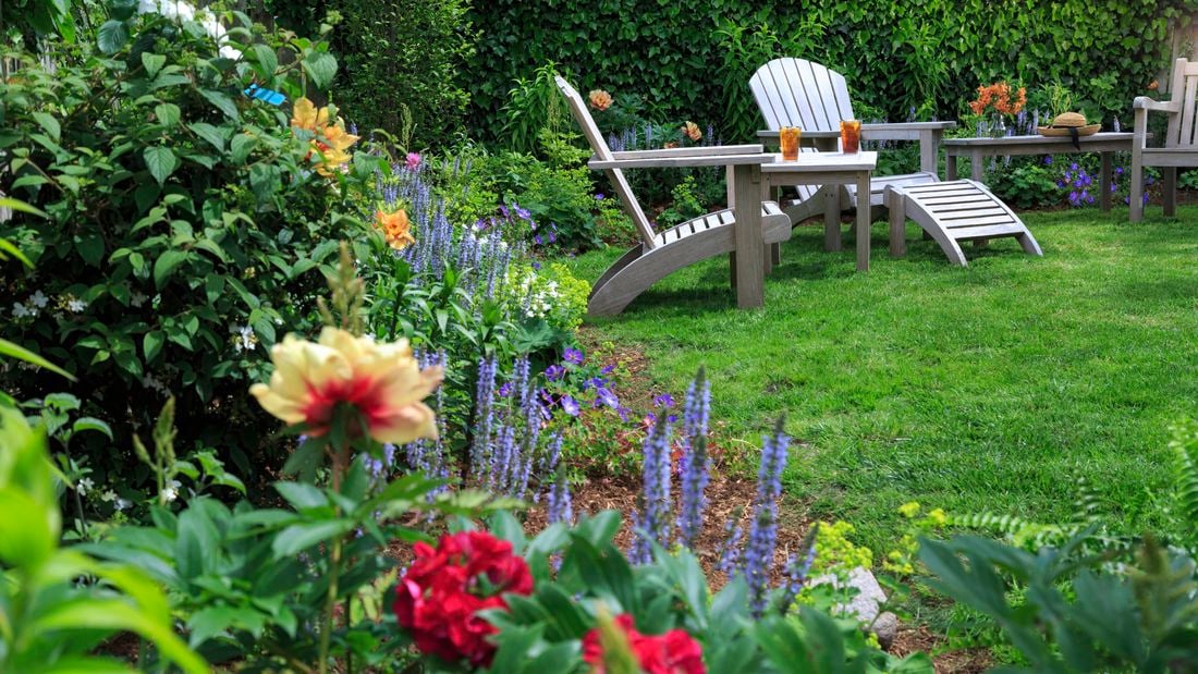 Garden with grass, flowers and outdoor furniture.