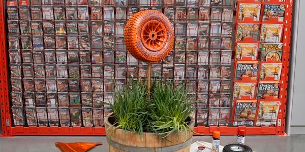 Wooden barrel with pole sticking out of it and tyre attached, painted orange.