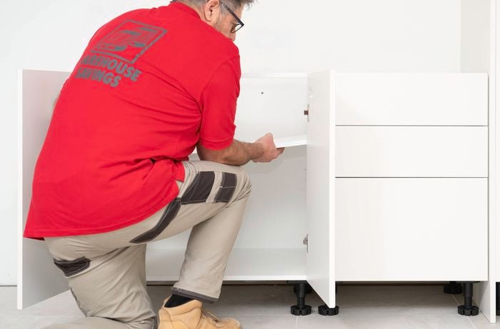 A Bunnings Team Member is installing the inner shelf inside the cabinet.
