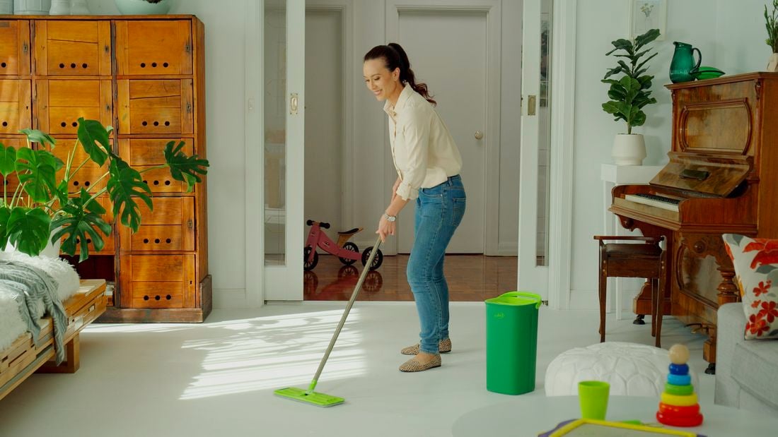 Woman mopping lounge room floor with Sabco mop and Sabco bucket on the side.