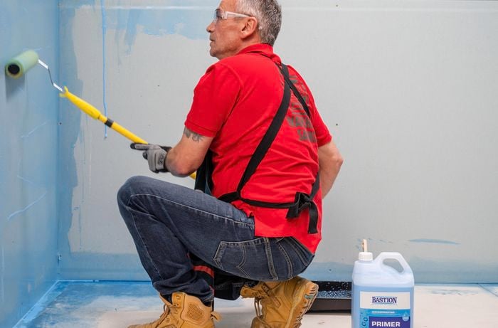 Man applying primer to wall. 