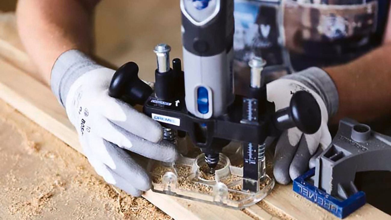 Two hands using a plunge router attachment on a rotary tool