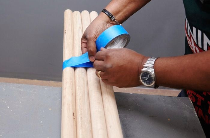 Lengths of dowel being taped together to cut bar stool legs of a matching length