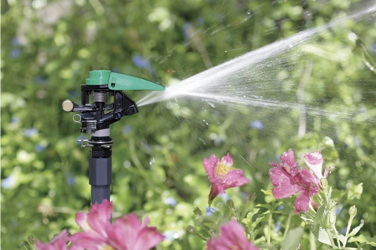 Close up of an impact head sprinkler with water spraying out