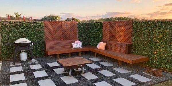 Outdoor entertaining area with timber bench seating, pavers and pebbles, and a firepit and BBQ