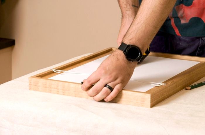 A Bunnings Team Member holding a piece of string on the back of a picture frame