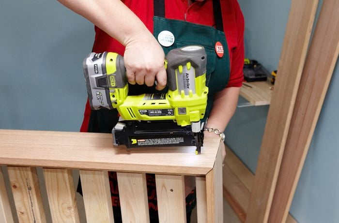Person using nail gun to nail bed frame together