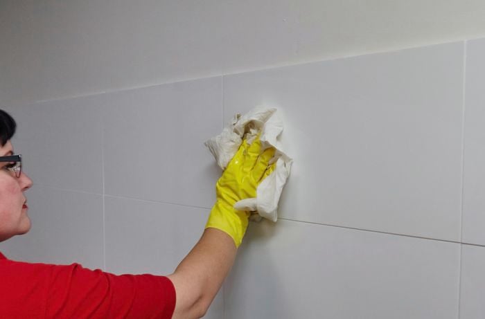 A person cleaning  splashback tiles in a kitchen