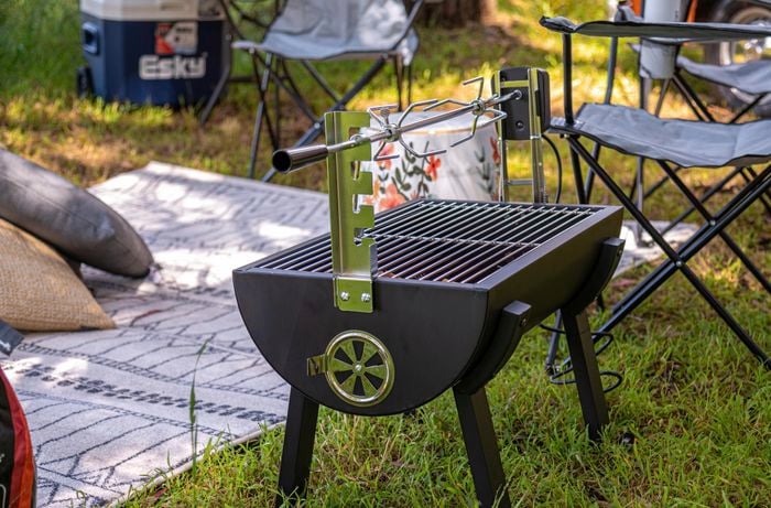BBQ spit at a camping site with outdoor camping chairs