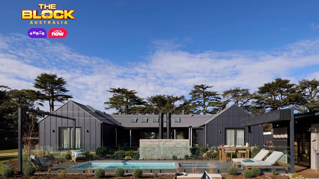 The back of a house with a pool in it, outdoor lounge, rocks area and an outdoor fireplace in i