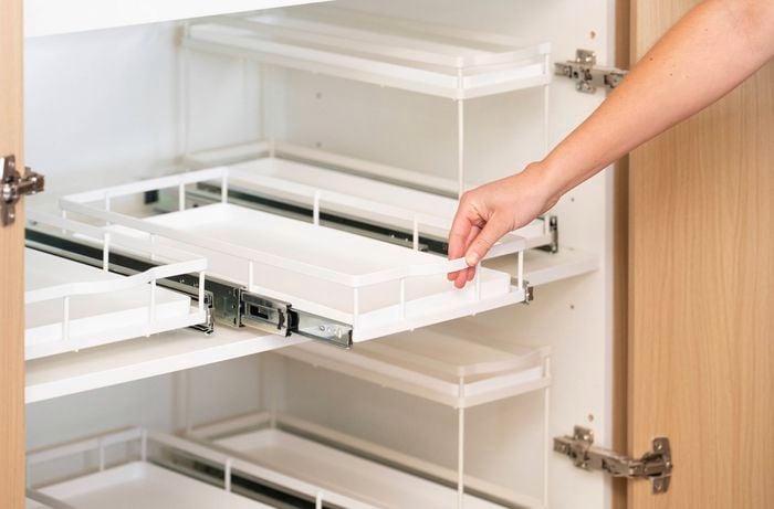 A person is opening a pull-out storage drawer to test smooth operation