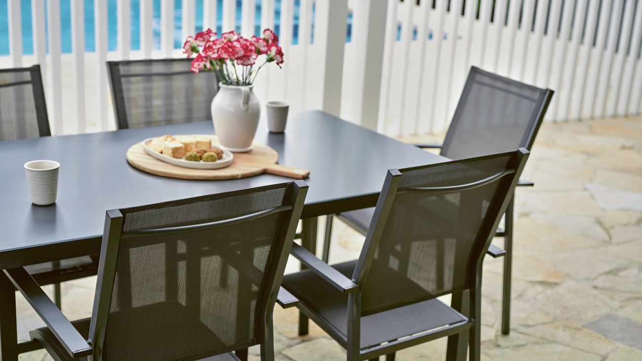 Powder-coated steel outdoor dining chairs and a table on a paved patio