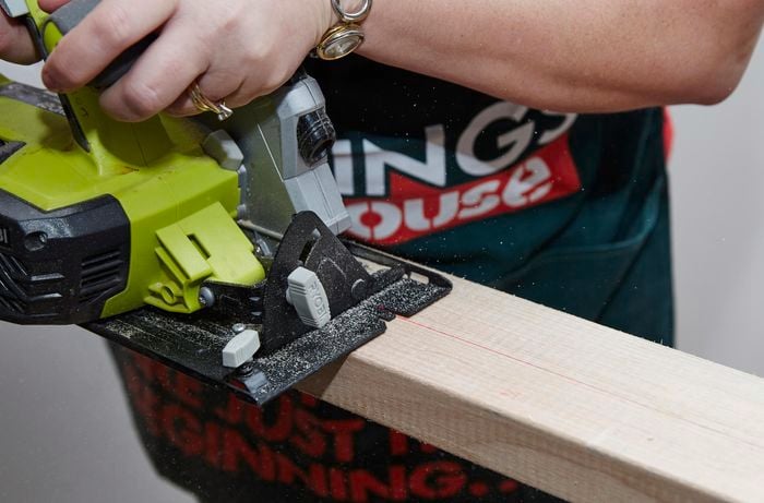 Person using circular saw to cut piece of timber.