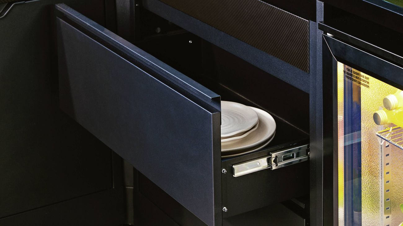 Partially open kitchen drawer of a modular outdoor kitchen with white plates