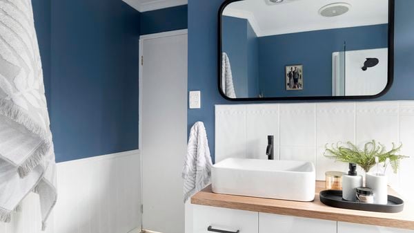 Bathroom with white vanity and sink, white tiles and blue wall.