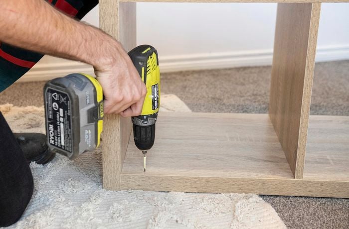 Plot holes being drilled into an assembled cube shelf for mounting on the wall