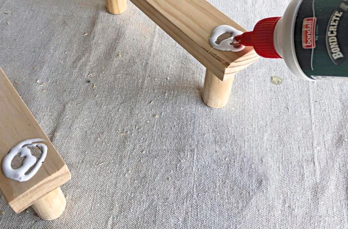 Glue being applied around a piece of dowel fitted into a pine board