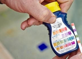 Person holding pool treatment product.