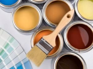 Lots of different coloured paint swatches, paint tins and a paint brush on a flat surface.