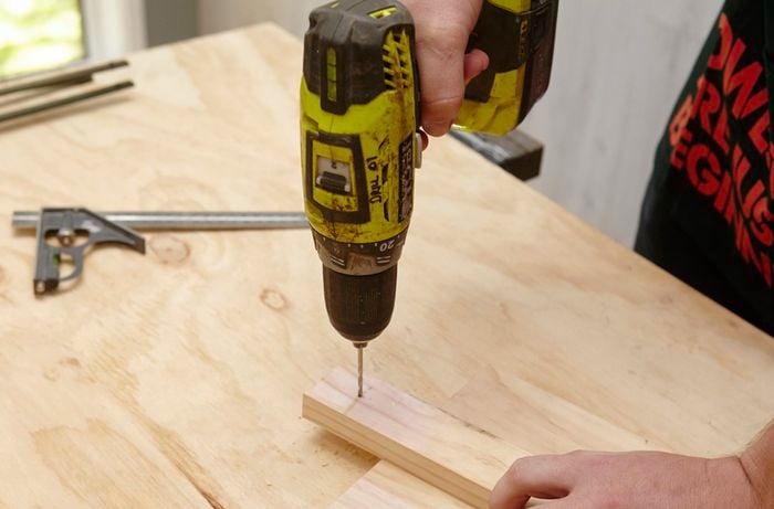 A person drilling a hole in a small piece of wood