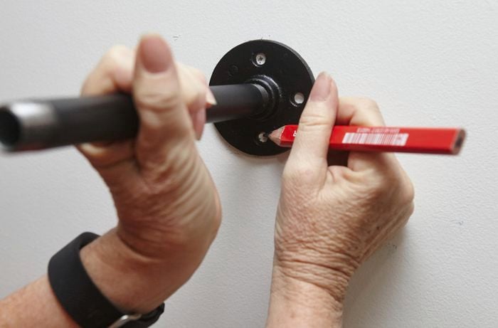 A person marking holes for shelf support flanges