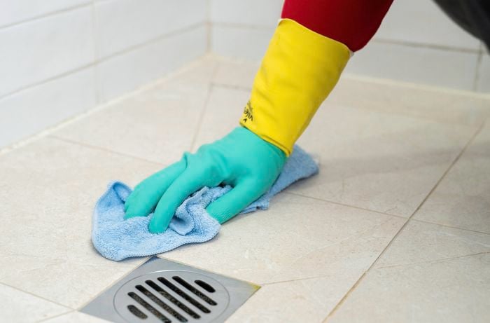 Cleaning and drying shower floor tiles around the drain to prevent mould