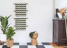 Green and white zig zagged towels hanging on a wooden towel rail on a white tiled wall