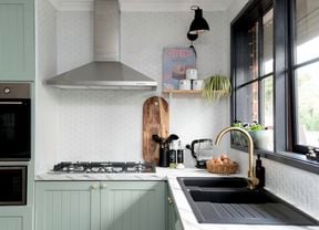 Kitchen with green cupboards and marble benchtop.
