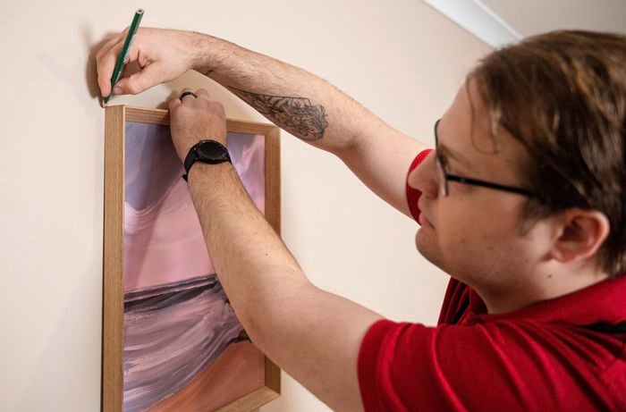 A Bunnings Team Member holding a pencil against a wall above a picture