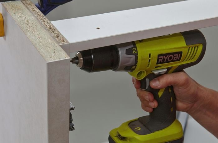 Person drilling screw into cabinet