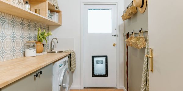 Updated laundry with doggy door, timber bench tops, timber shelving and mosica green and blue wall tiles
