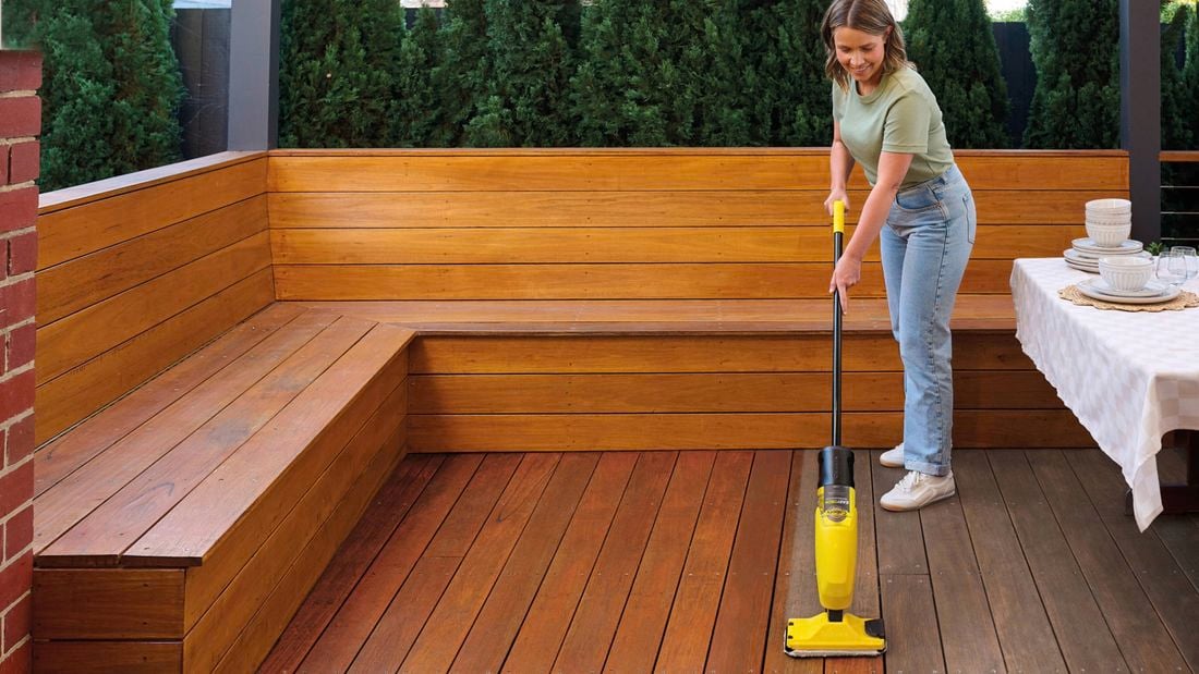 A woman applying Cabot’s Easy Deck onto timber decking