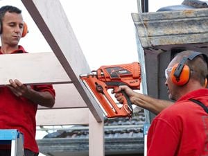 Person attaching rafters into carport frame using a nail gun