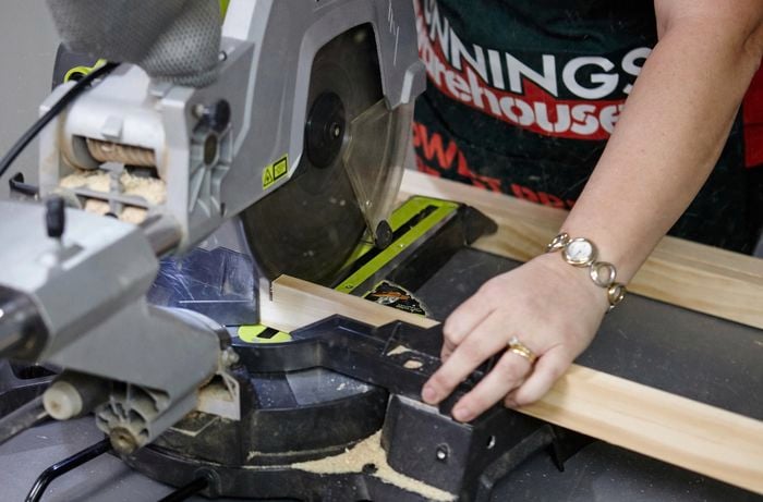 Person using circular saw to cut piece of timber.