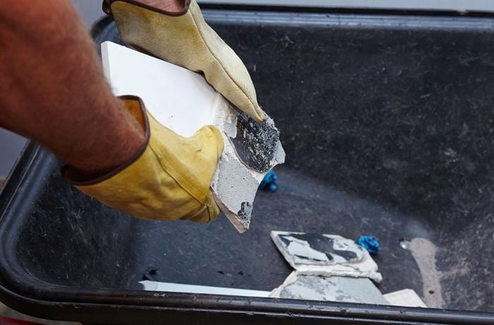 Loose broken tiles being discarded into a wheel barrow