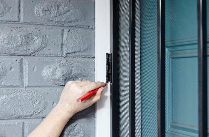 A pencil being used to mark the door frame for chiselling away enough wood to install hinges