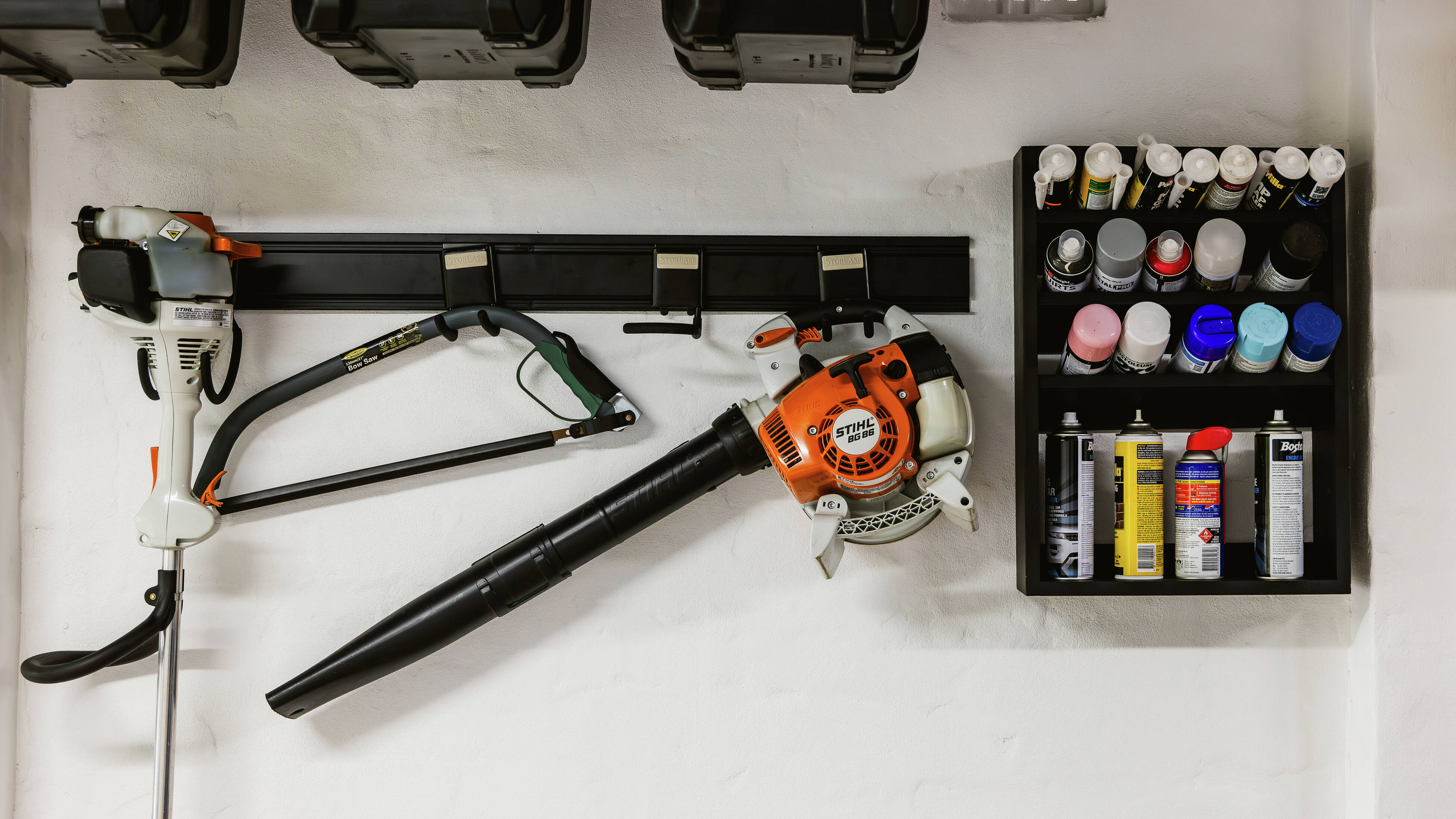 Wall-mounted garden tools and storage rack inside a garage.