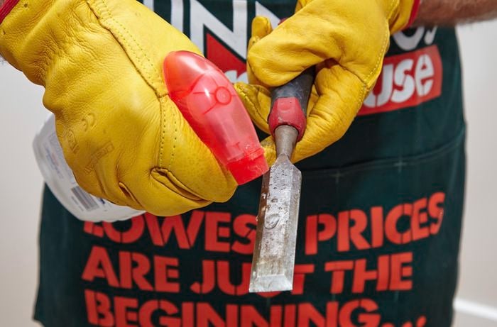 A person spraying a chisel with an abrasive chemical