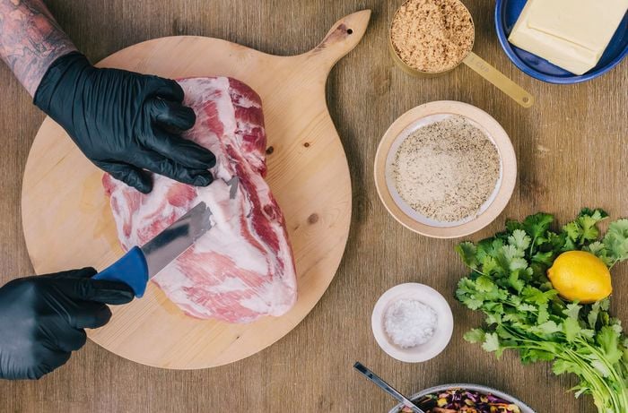 Person trimming fat off a pork shoulder