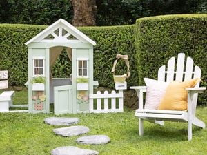 Backyard setting with Easter craft projects including egg hunt sign and painted cubby house