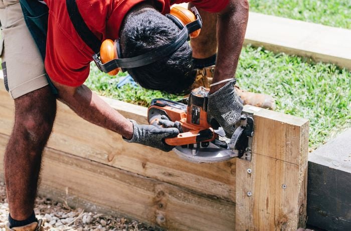 A Bunnings team member using a circular saw to cut the top from a retaining wall