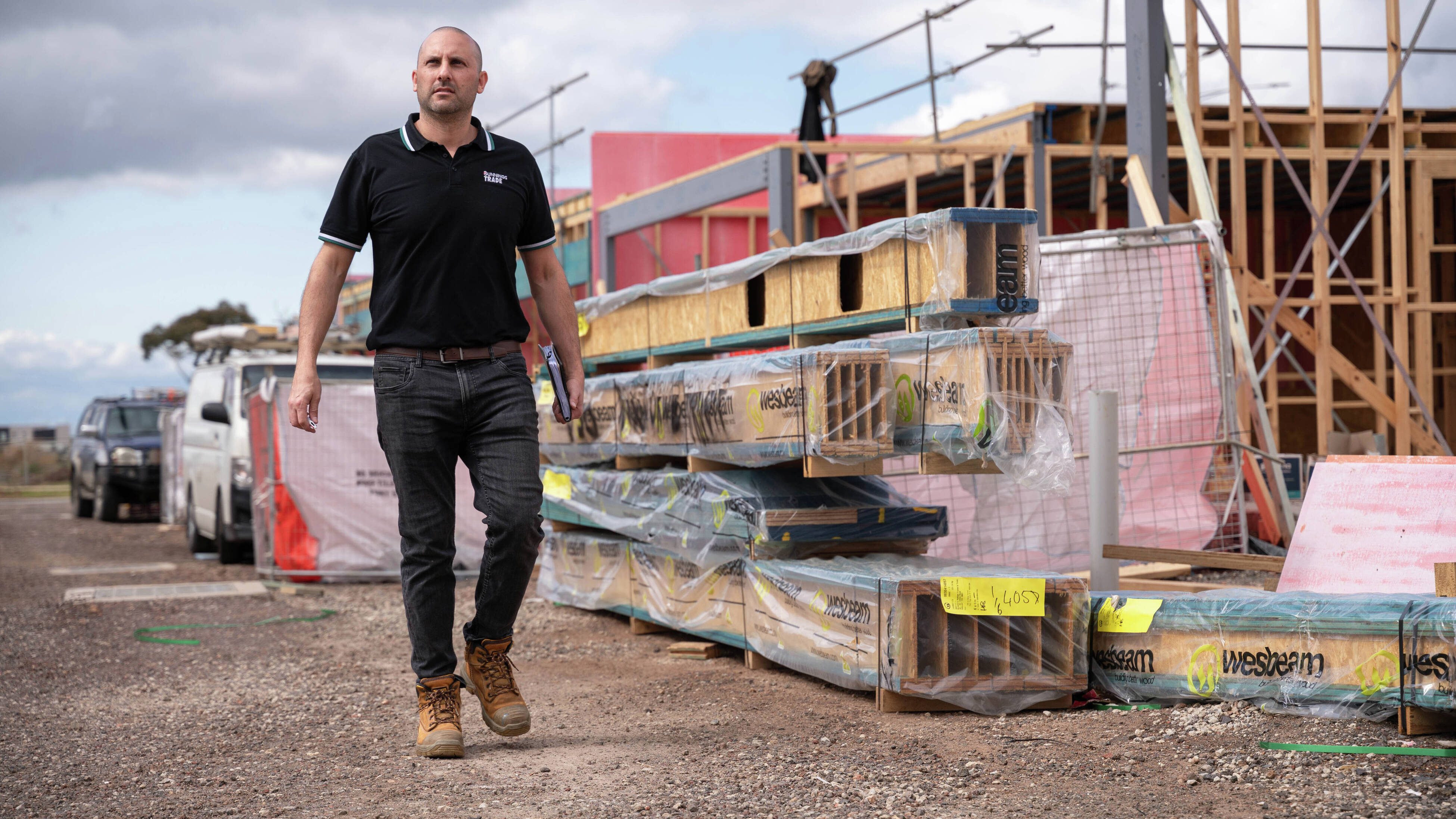 A building site at frame and truss stage with a fence.