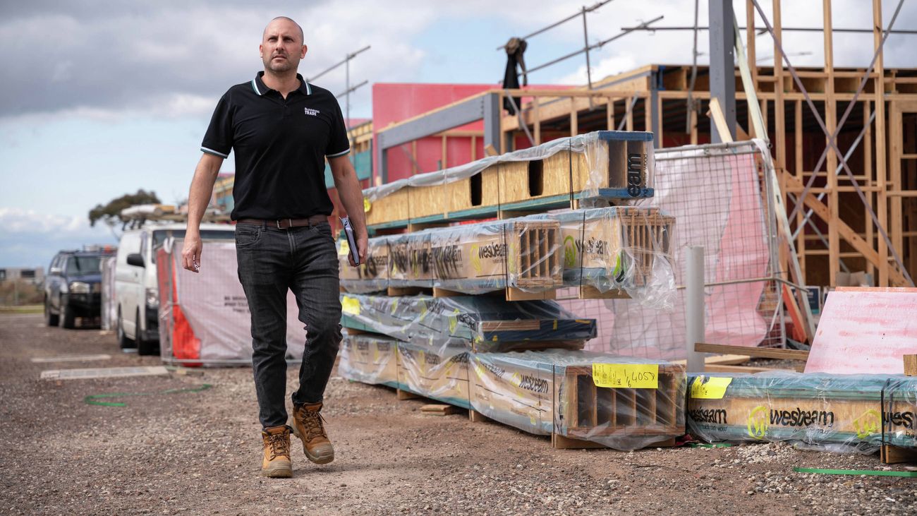 A building site at frame and truss stage with a fence.