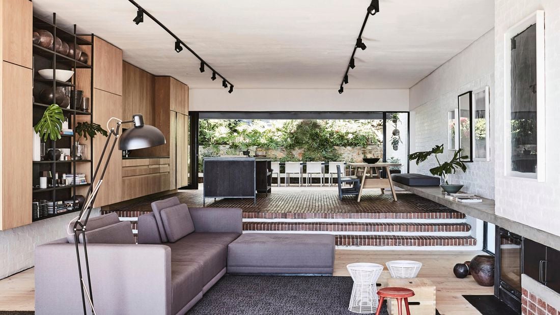 Living room with sunken lounge and long strips of pendant lighting.