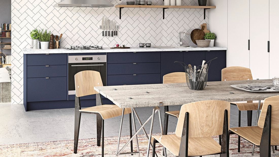 An open plan kitchen with navy cabinets, wooden shelves and pale tiled walls