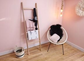 A wooden towel ladder with scarves leaning against a pink painted wall