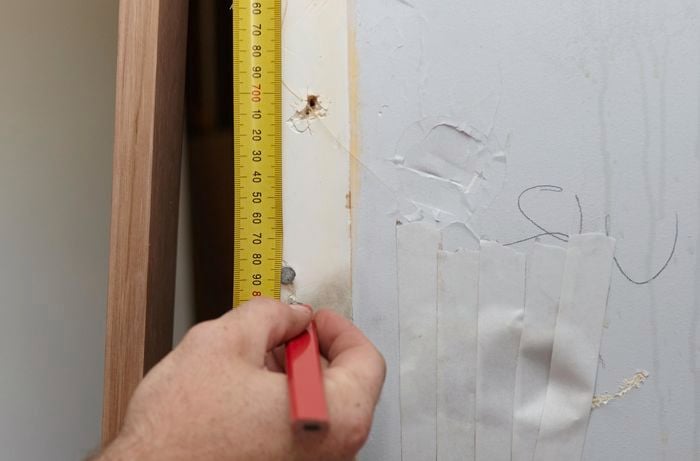 A bare wall being measure for a replacement door jamb